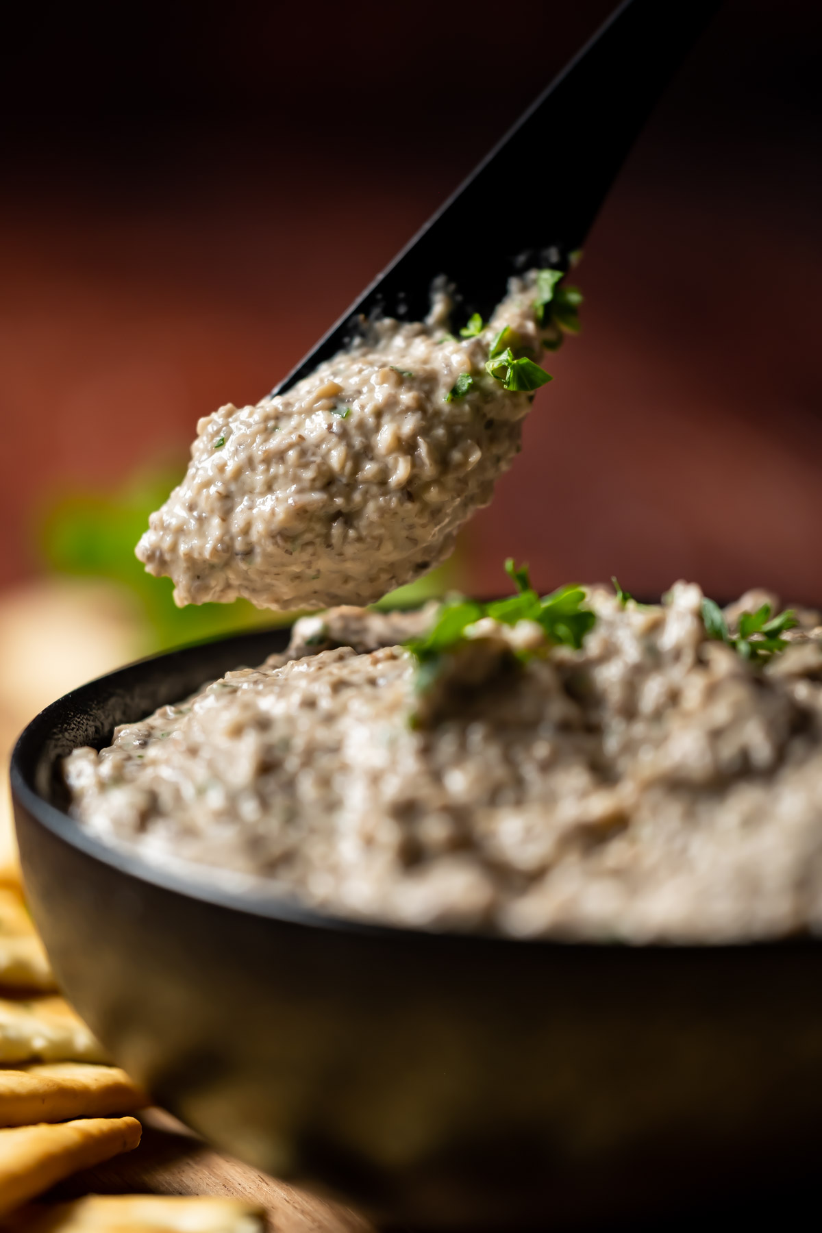 Vegan mushroom pâté in a black bowl with a knife.