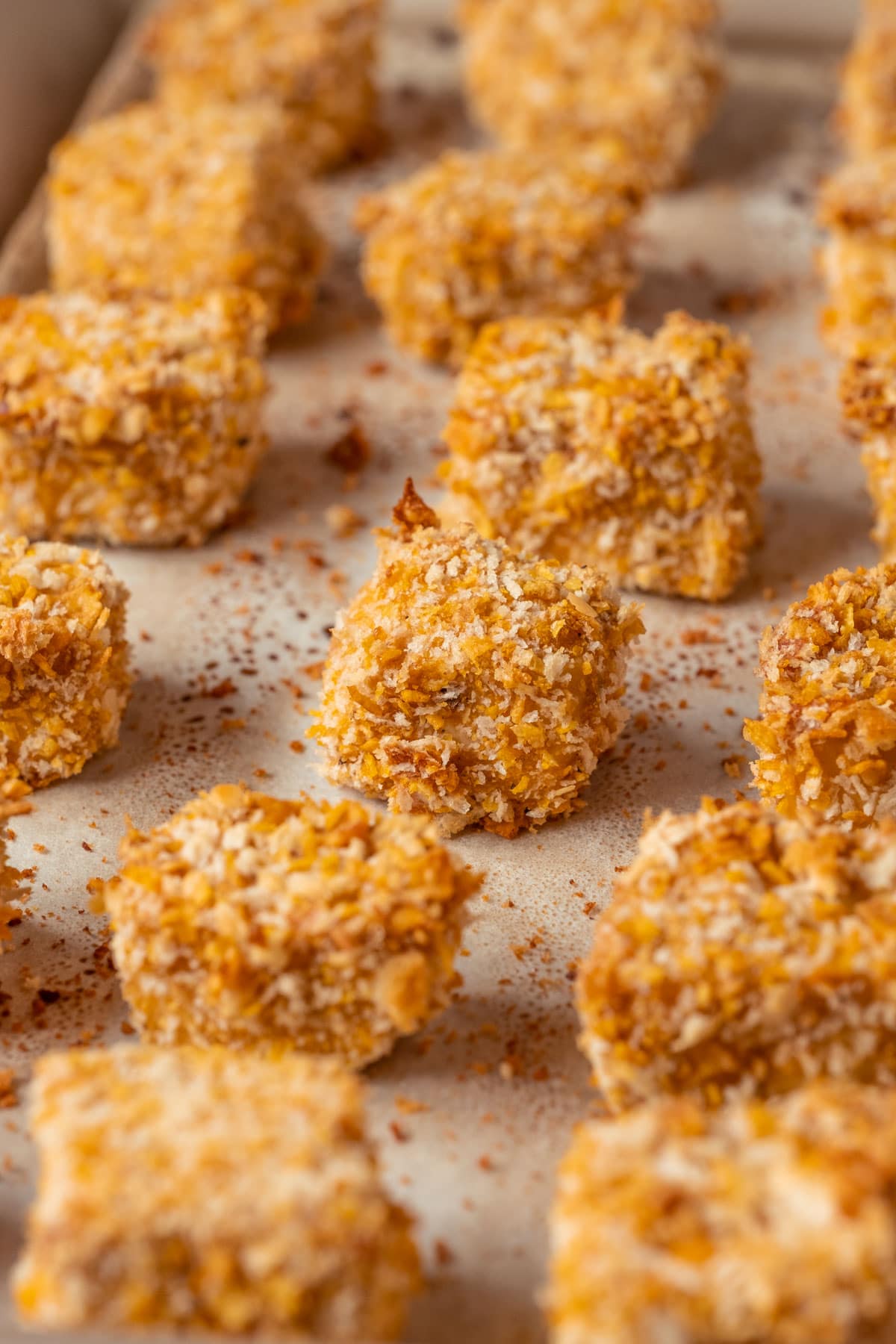 Vegan chicken nuggets on a parchment lined baking sheet.