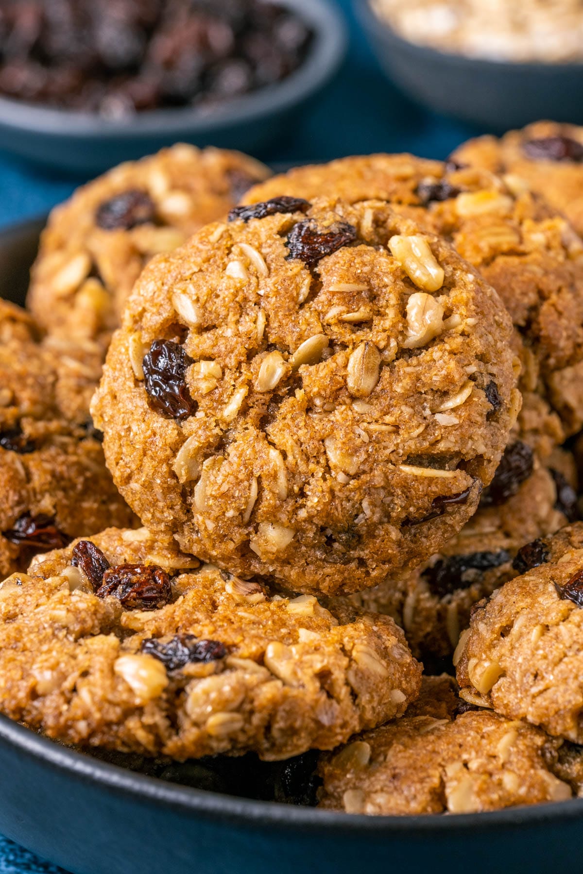 Vegan oatmeal raisin cookies stacked up on a black plate.