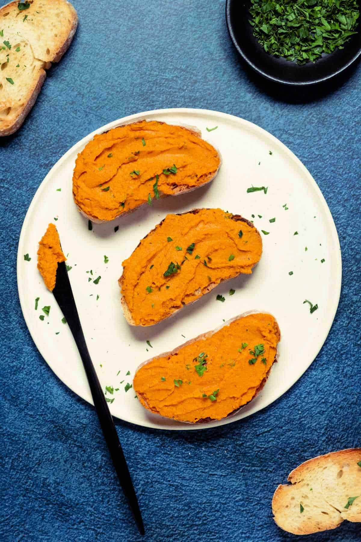 Slices of toast spread with vegan pâté on a white plate.