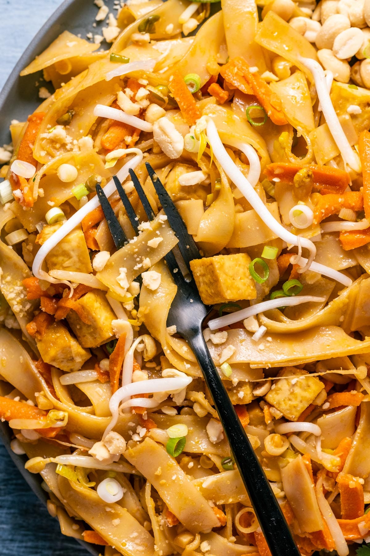 Vegan pad thai on a gray plate with a fork.