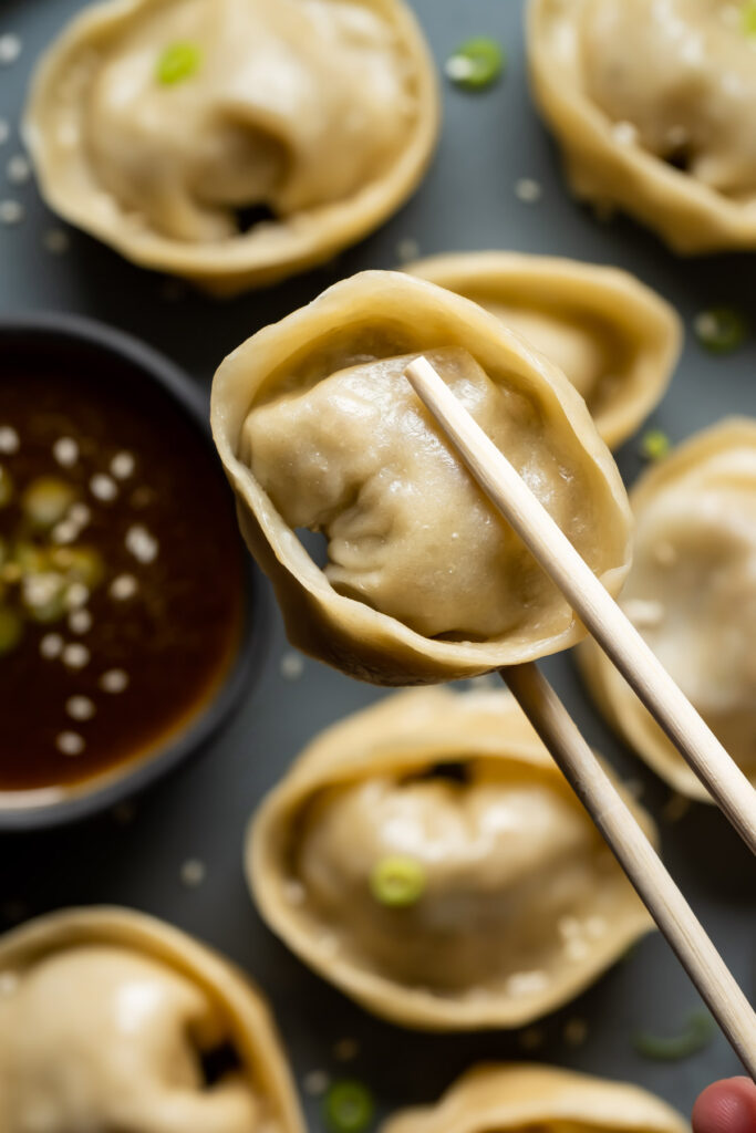 Chopsticks holding a dumpling.