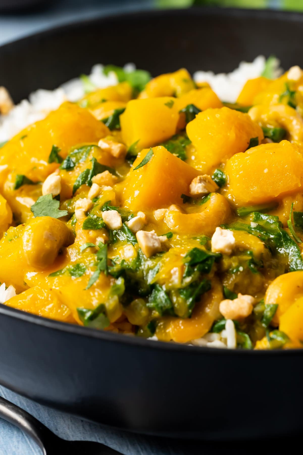 Thai pumpkin curry with rice in a black bowl.