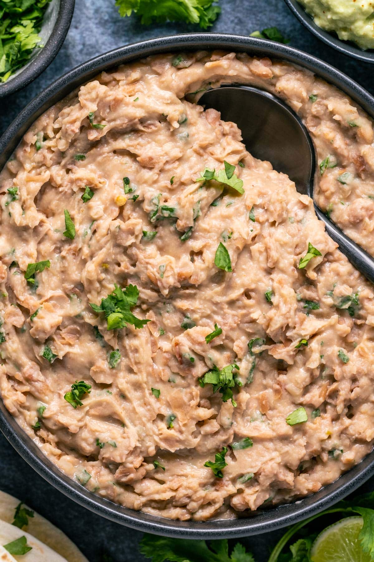 Vegan refried beans in a black bowl with a spoon.