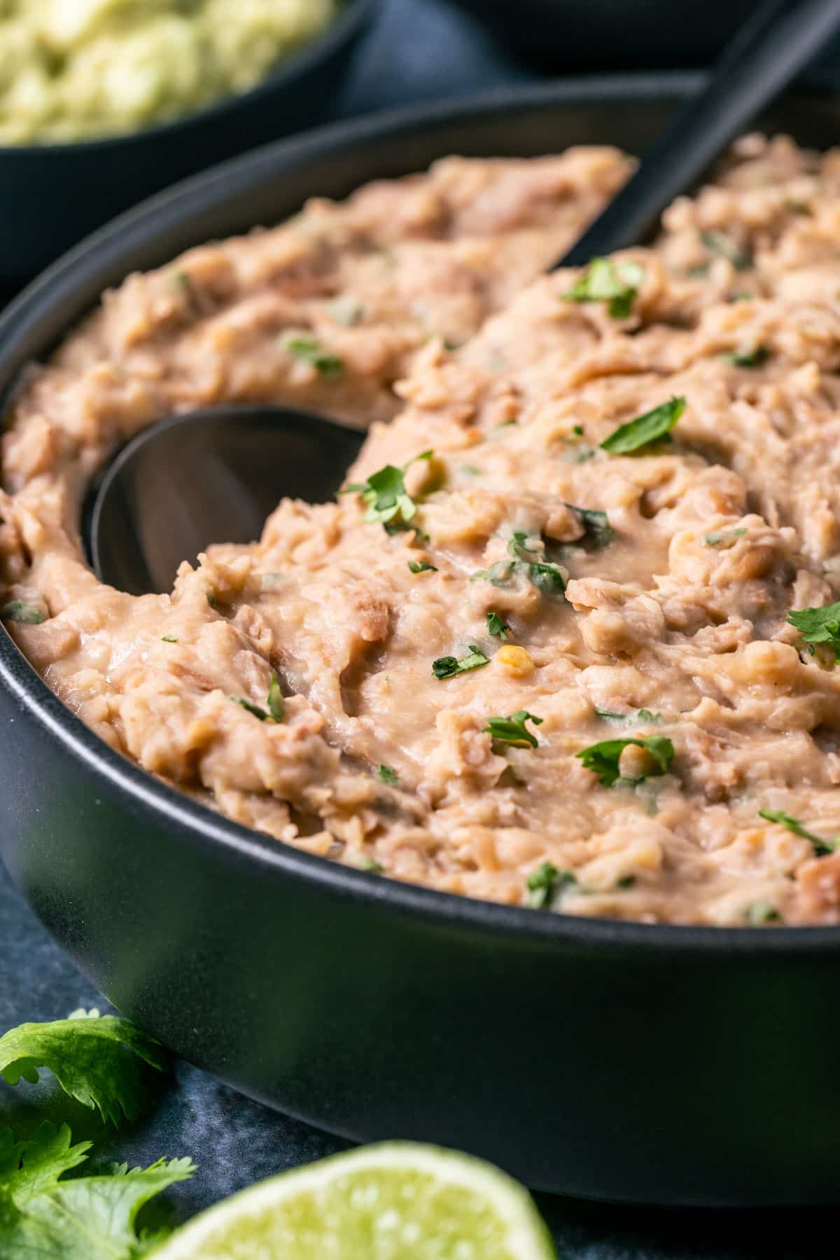 Vegan refried beans in a black bowl with a spoon.