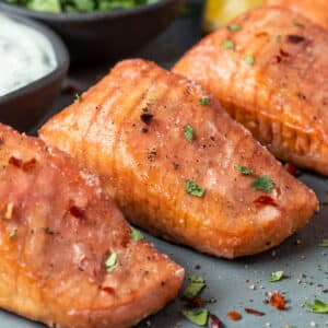 Vegan salmon on a gray plate with vegan tartar sauce and chopped cilantro.