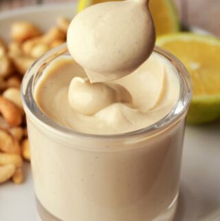 Vegan sour cream in a glass jar with a spoon.