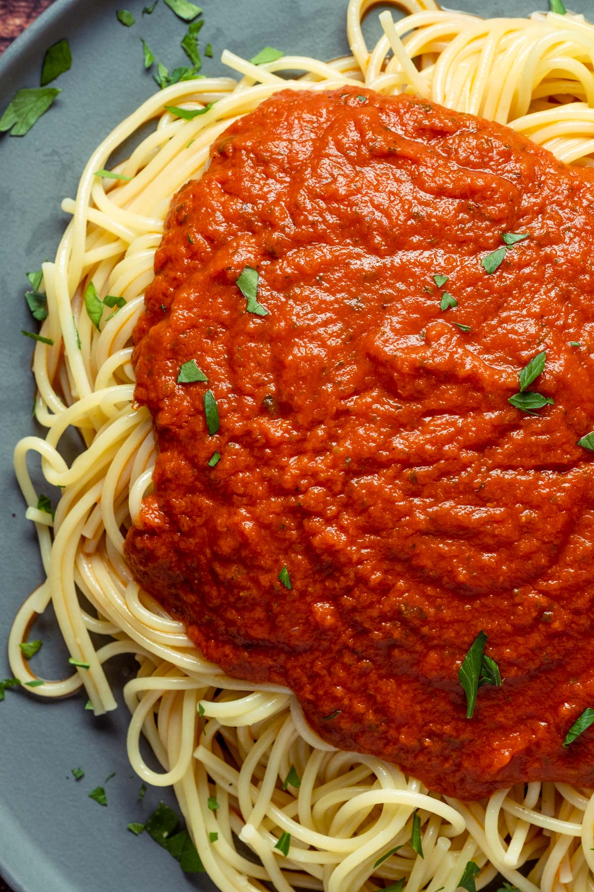 Vegan spaghetti sauce over spaghetti on a gray plate.