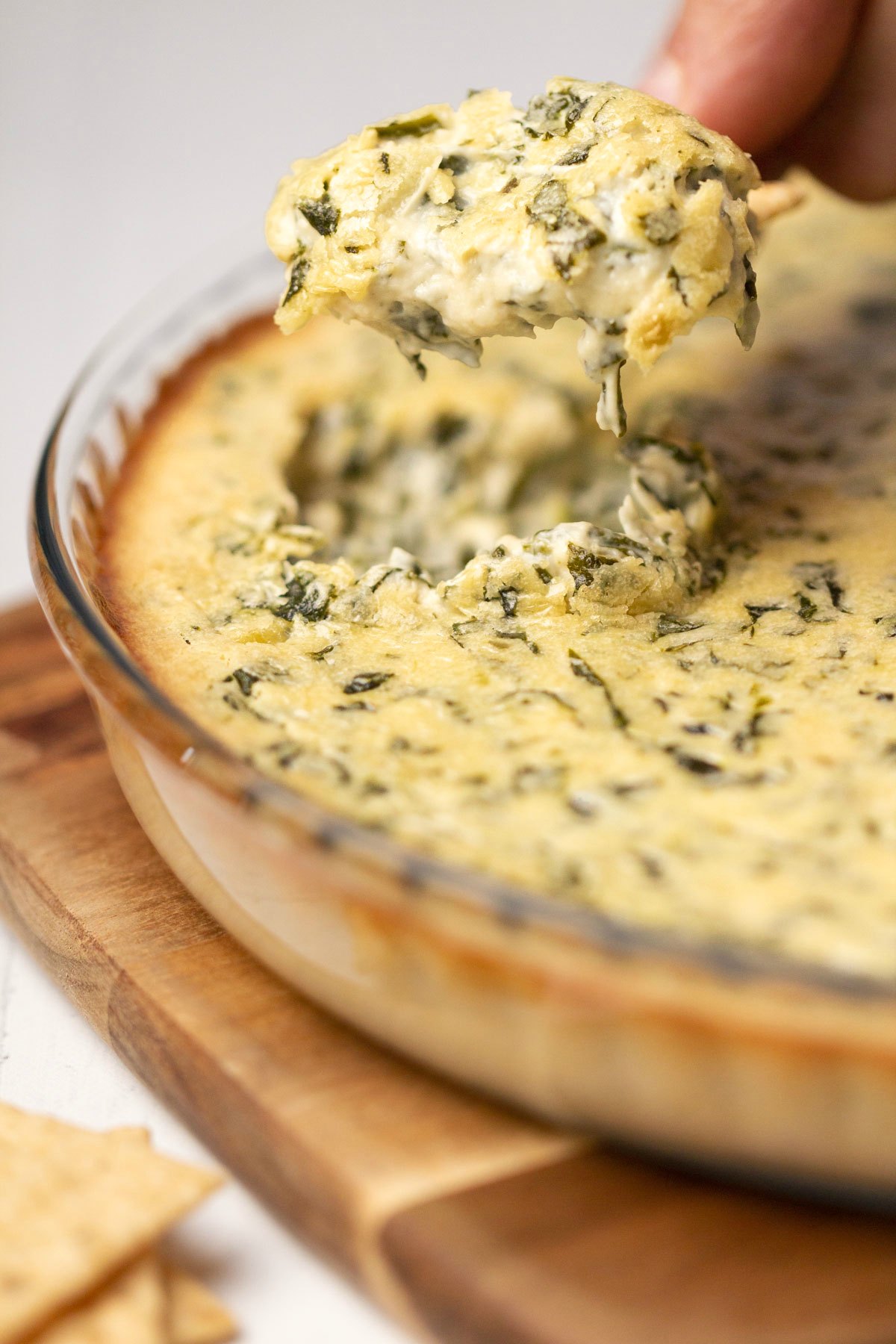 A cracker dipping into vegan spinach dip. 