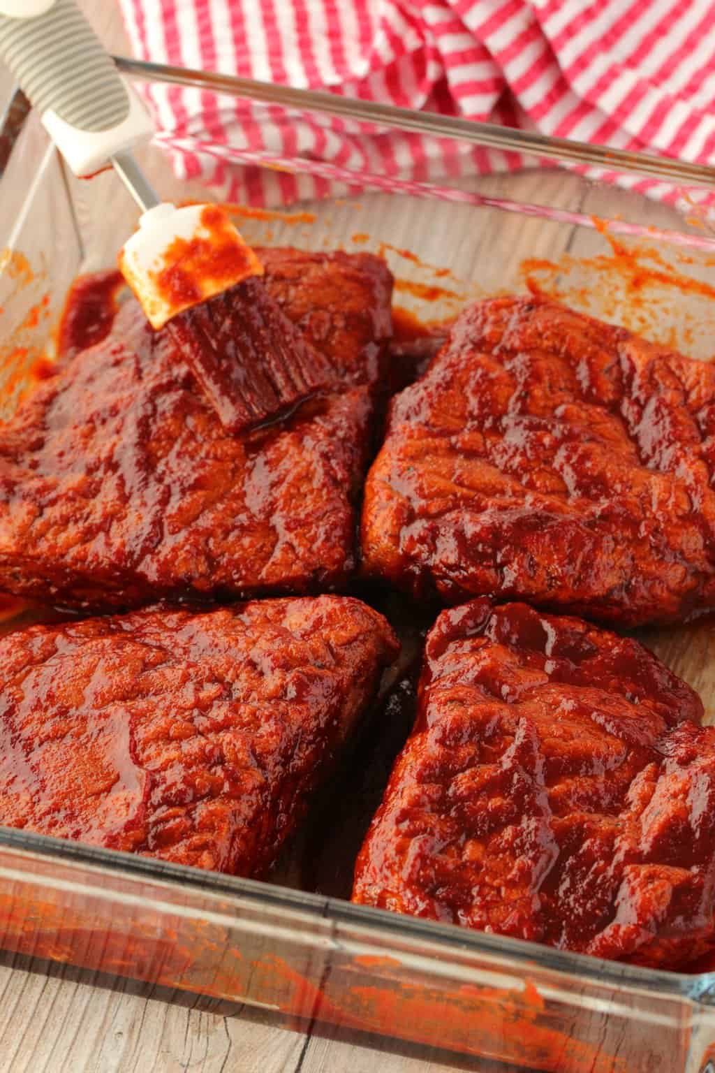 4 Vegan steaks brushed with marinade sauce in a glass dish. 