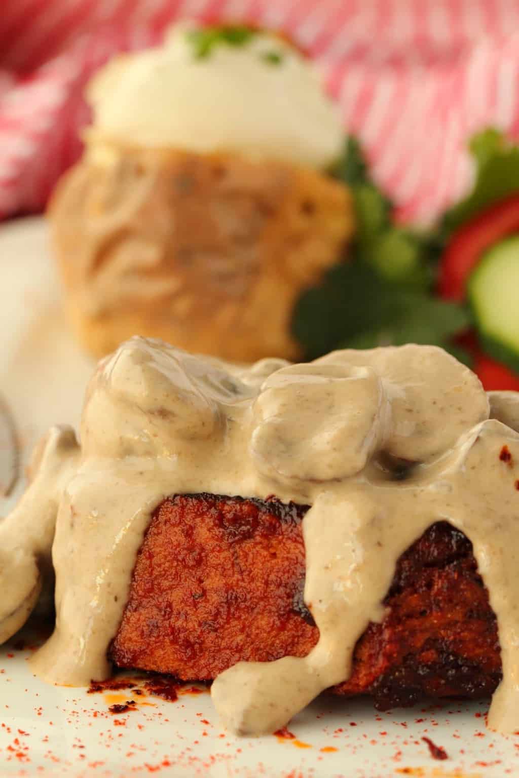 Vegan Steak covered in mushroom sauce on a white plate. 