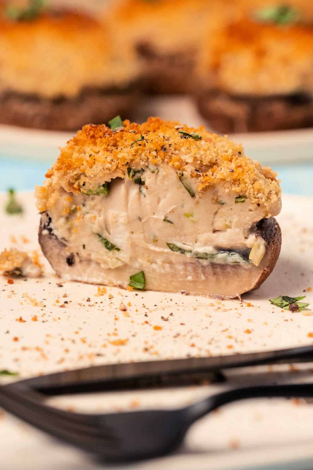 Stuffed mushroom cut in half on a white plate.