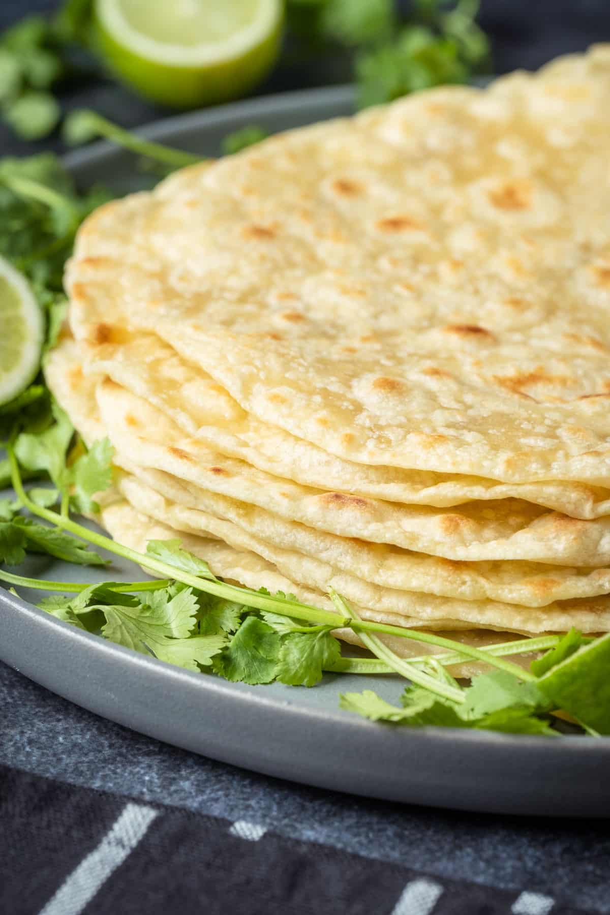 Stack of vegan tortillas on a plate with fresh cilantro.