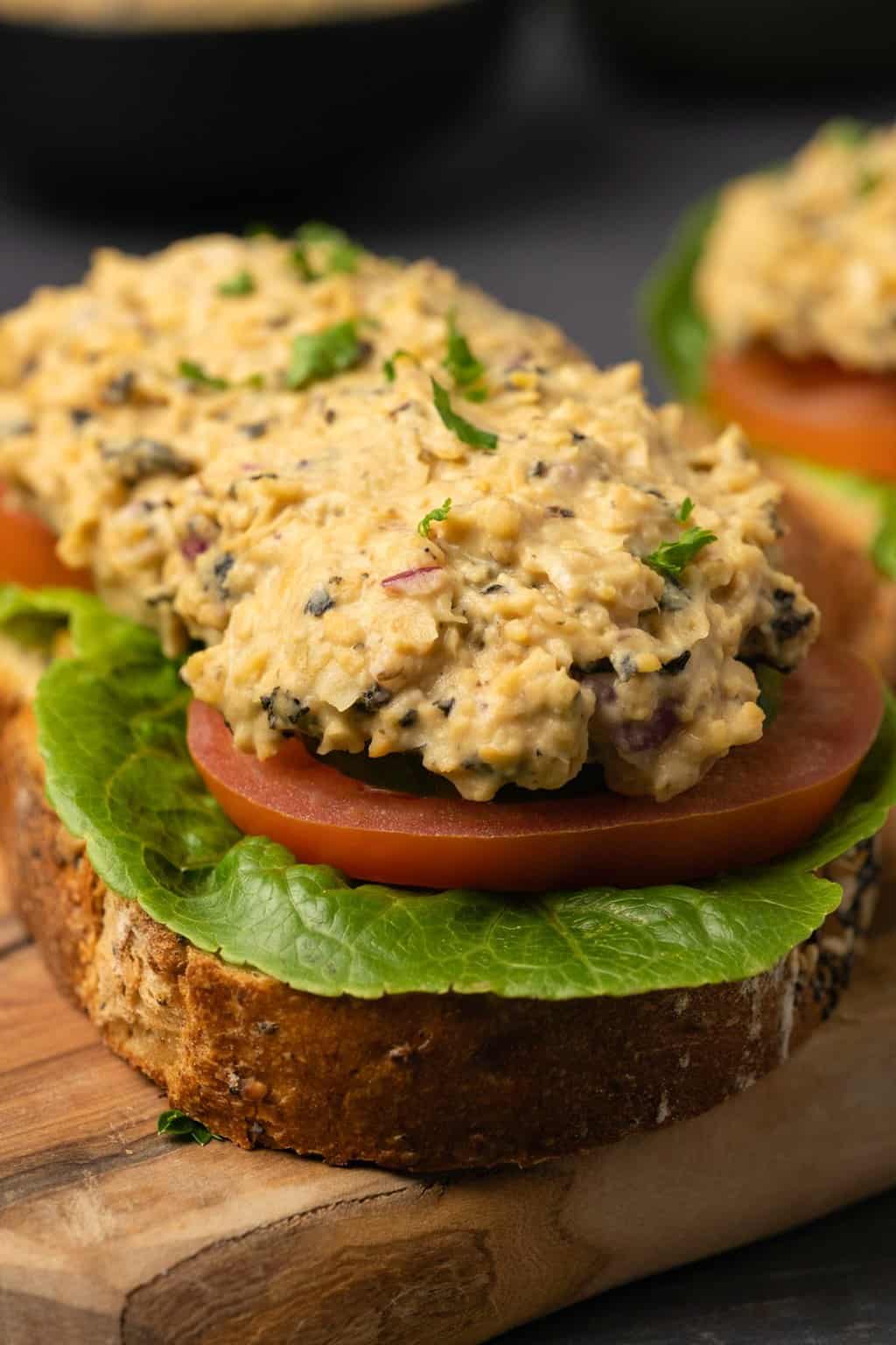 Vegan tuna on an open faced sandwich on a wooden board.