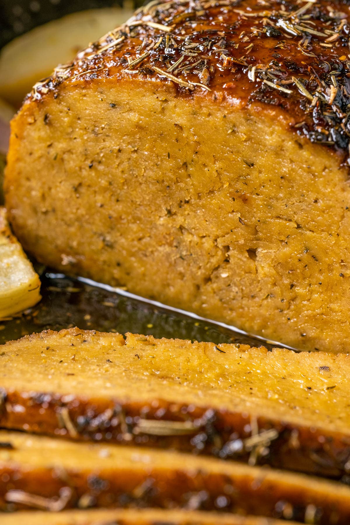 Sliced vegan turkey roast in a roasting pan.