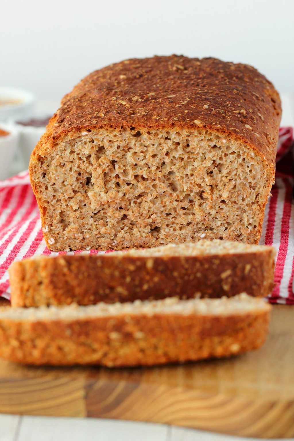 Wholewheat Bread on a wooden board with a red and white striped napkin. 